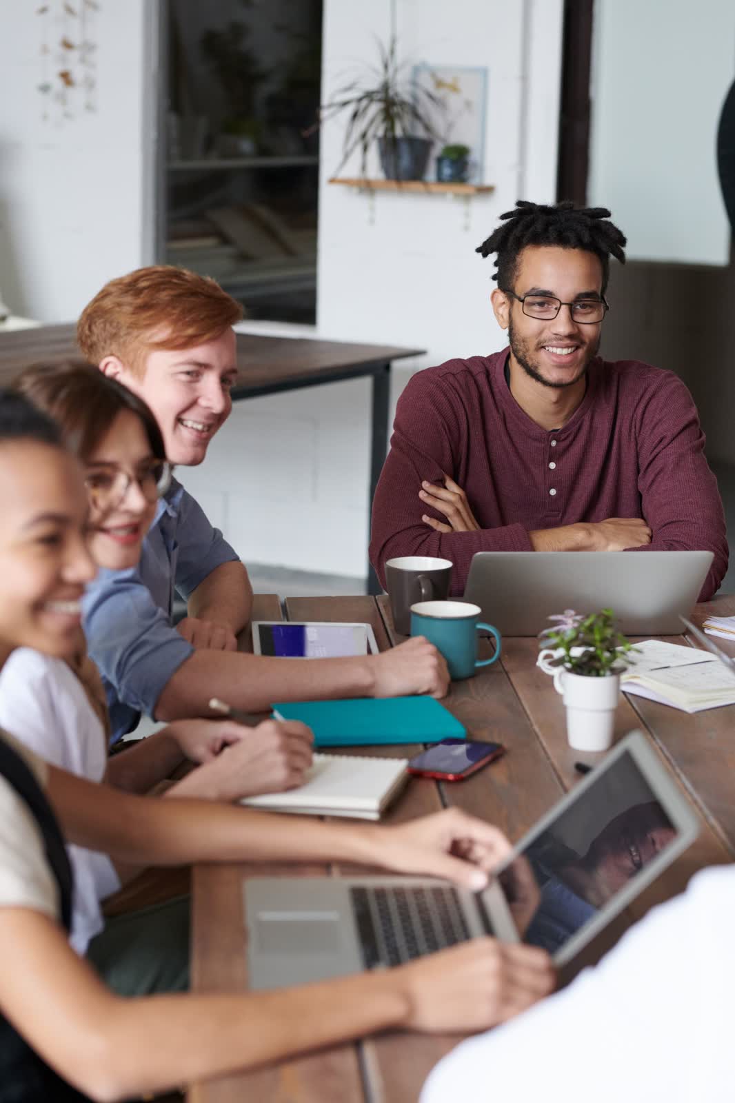 Small business team of five working together around a table, covered by a group health plan